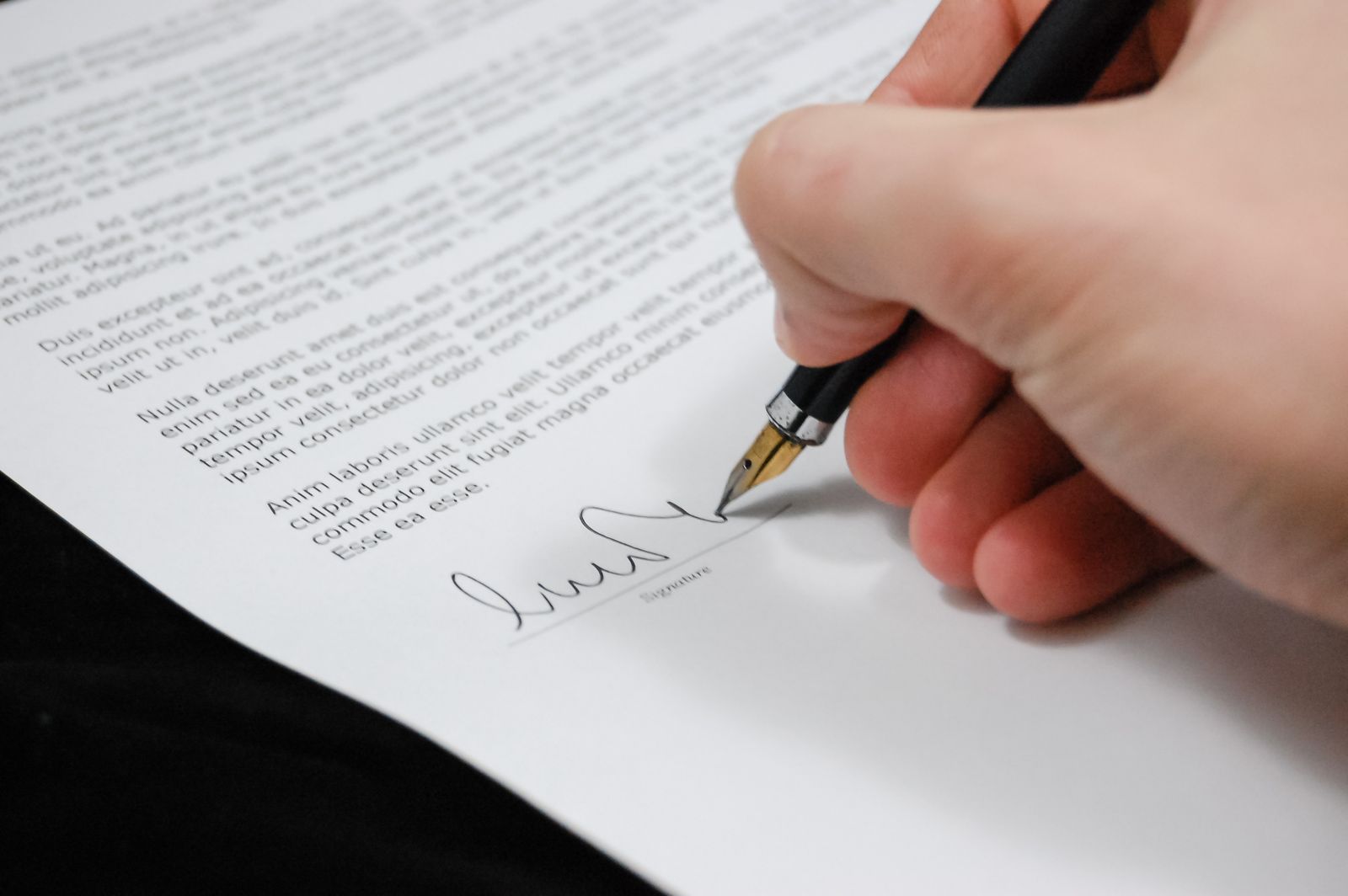 Mão assinando um contrato com caneta-tinteiro