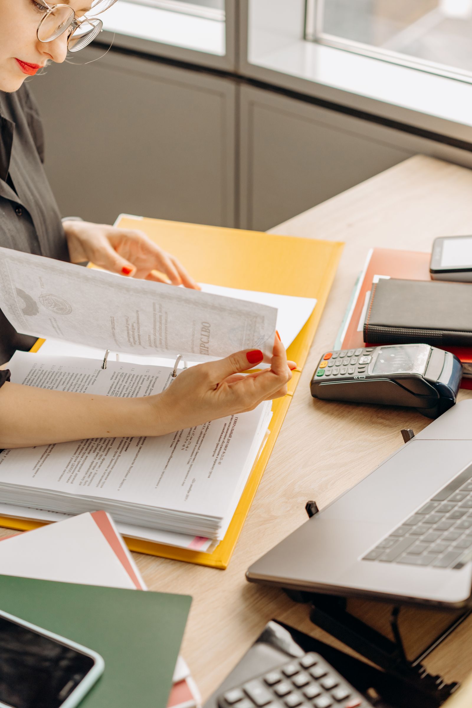 Mulher revisando documentos financeiros em uma mesa de madeira