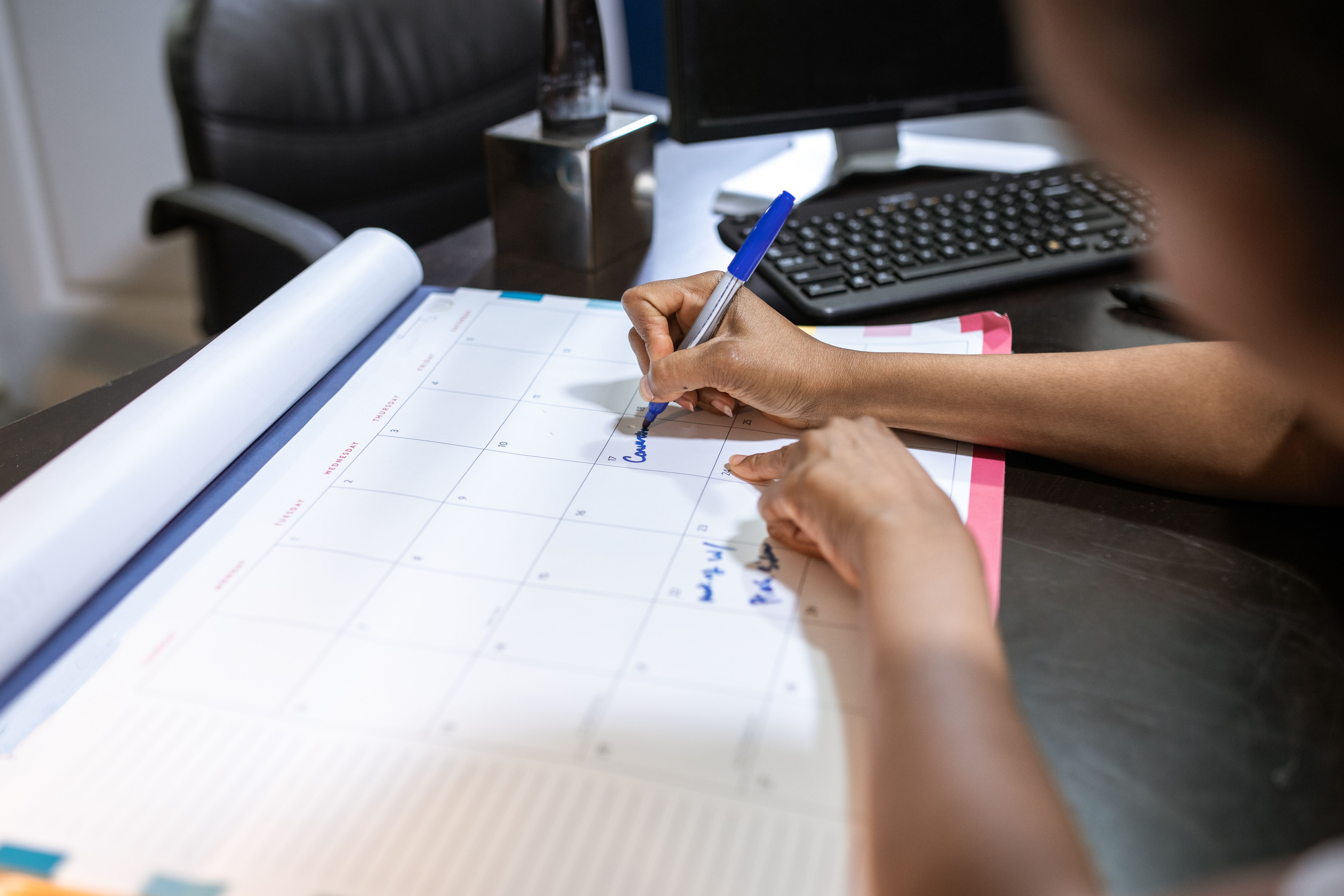 Mulher organizando a agenda de compromissos em um calendário de mesa