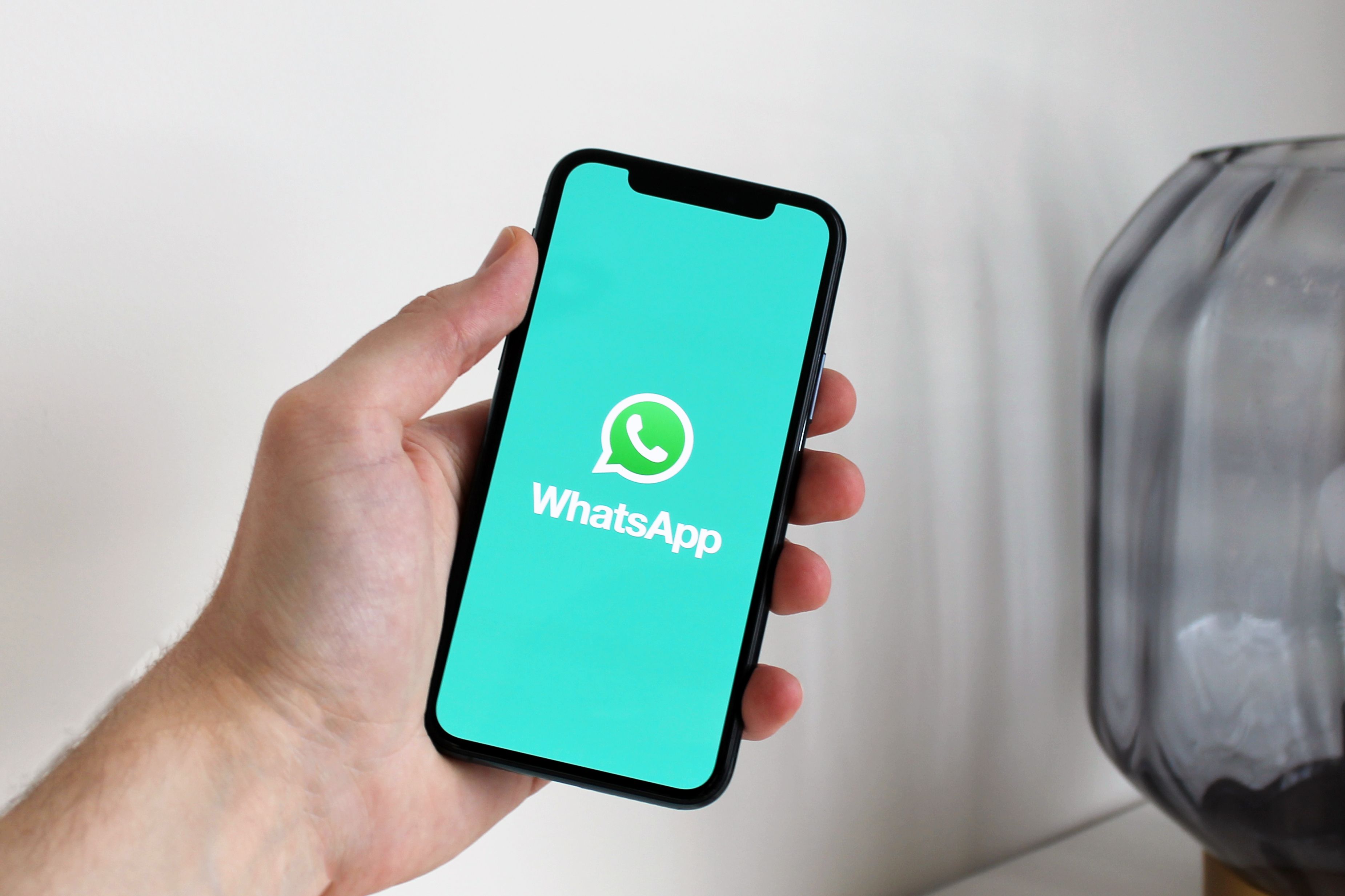 Mão segurando celular com a tela do WhatsApp aberta