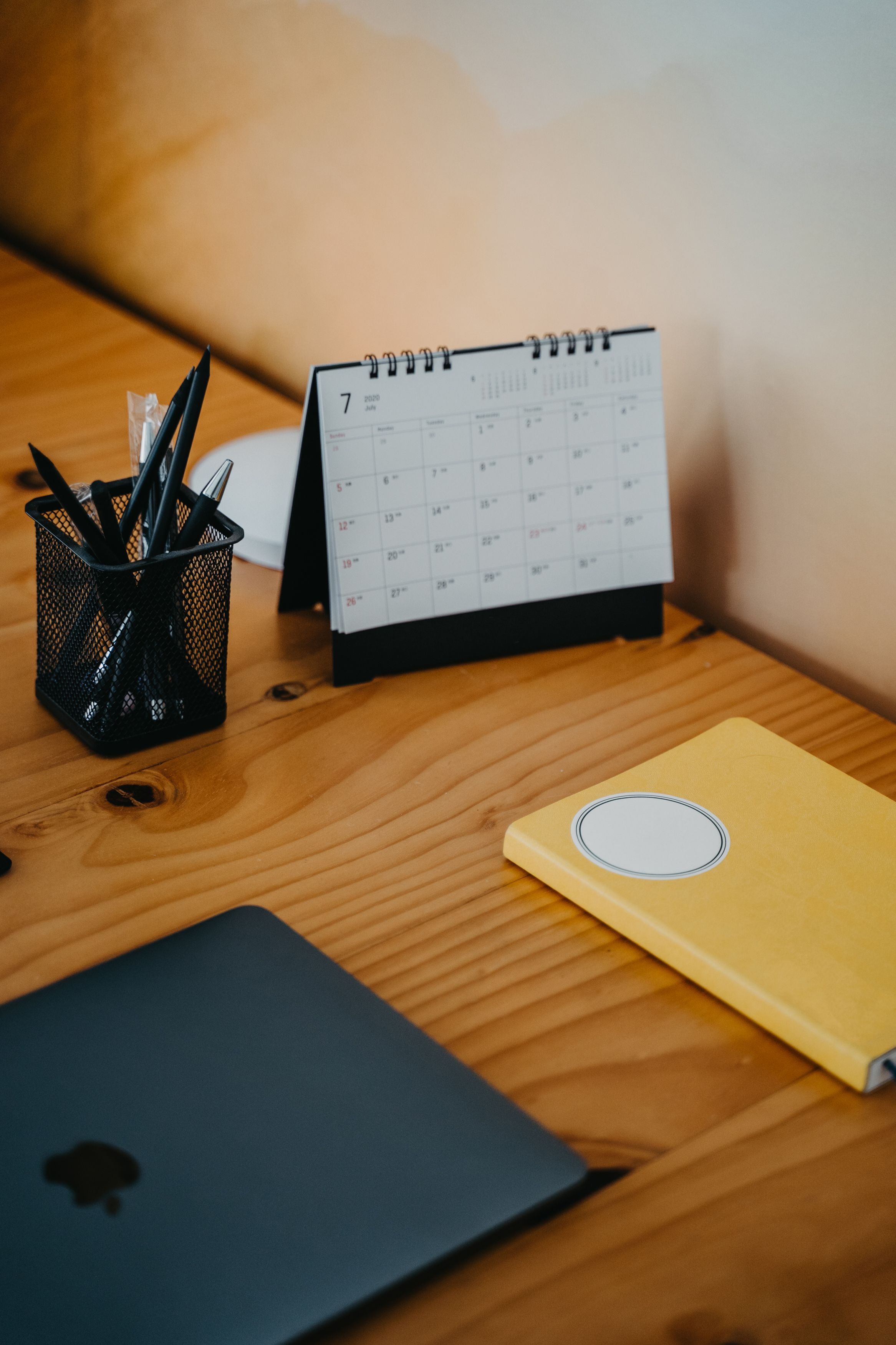 Mesa de escritório organizada com calendário, laptop e caderno de planejamento